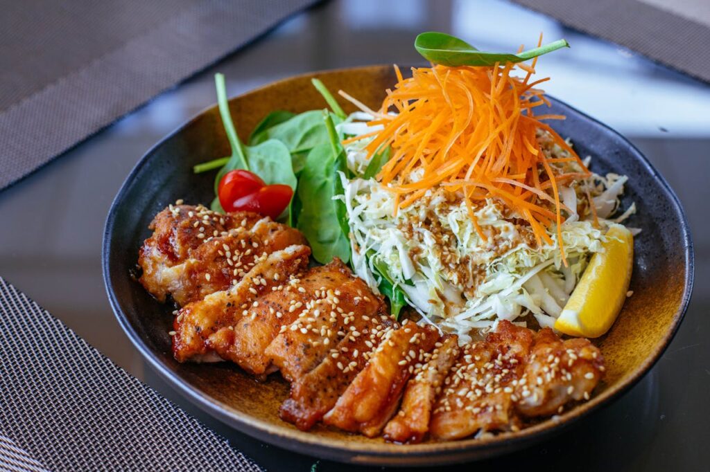 A vibrant and healthy salad bowl with grilled chicken, fresh veggies, and a lemon wedge.