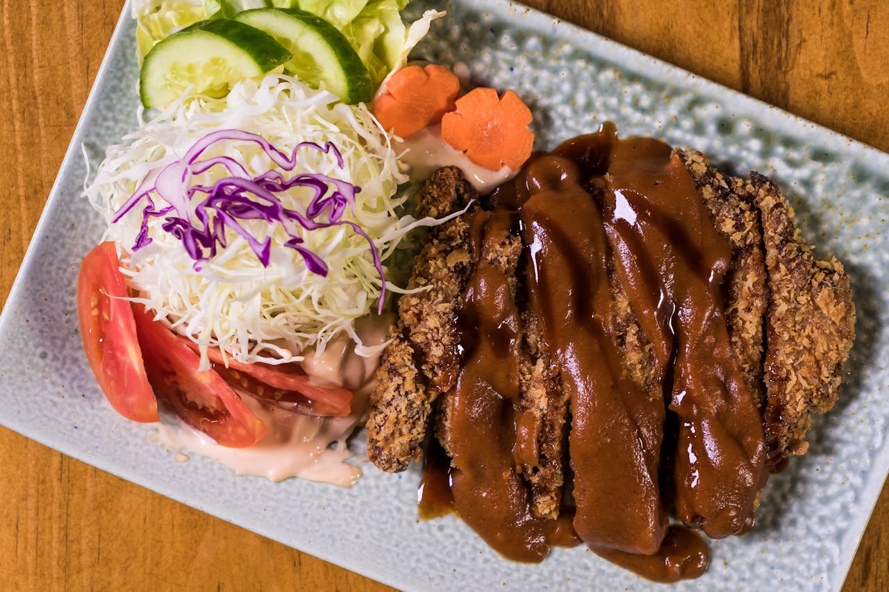 Crispy tonkatsu served with fresh vegetables and sauce, perfect for Japanese cuisine enthusiasts.