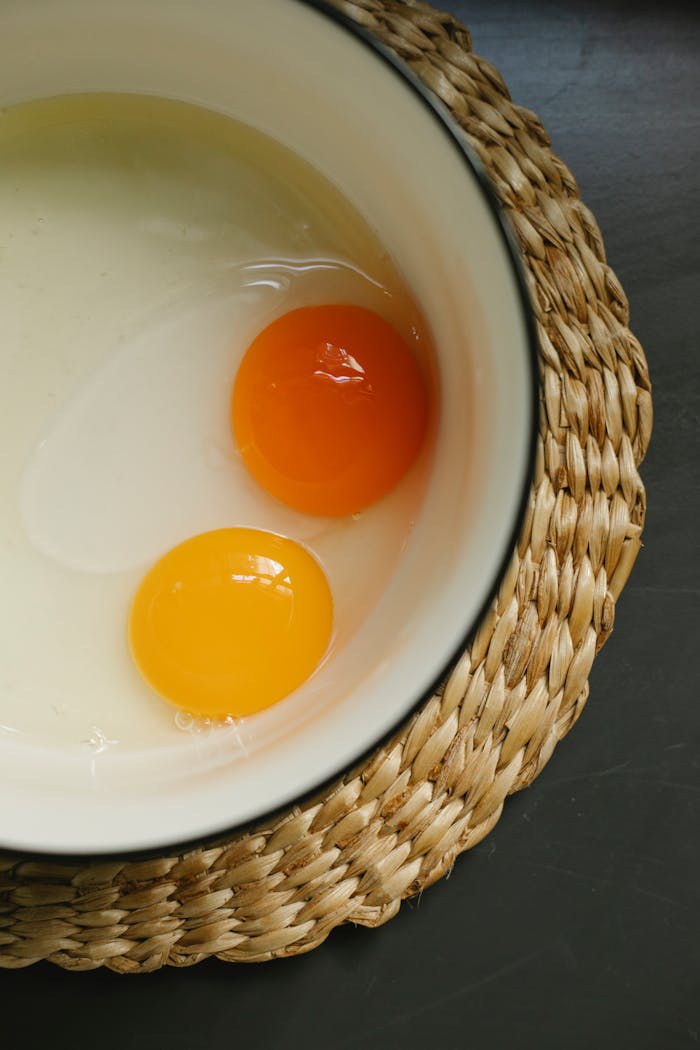 services-04 Overhead view of raw egg yolks in a bowl, perfect for cooking and culinary concepts.